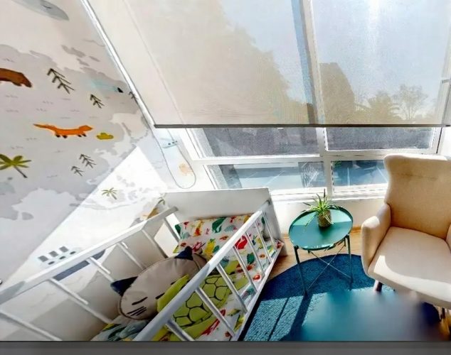 Tercer dormitorio con imagen de una cuna y una mesa pequeña.